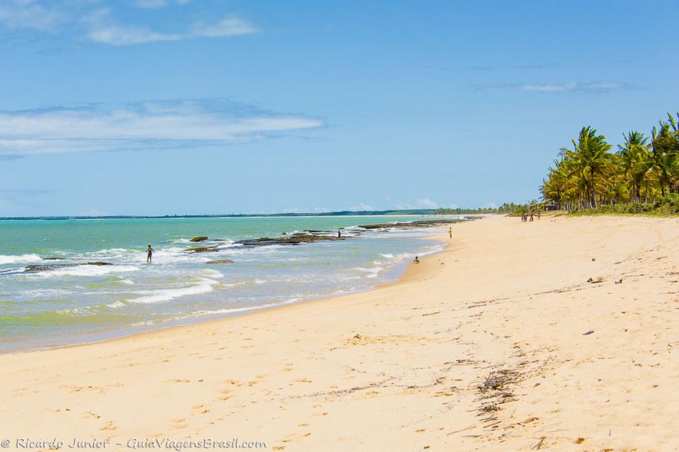Imagem de um dia lindo e turistas nas águas e nas areias da Praia de Caraiva.